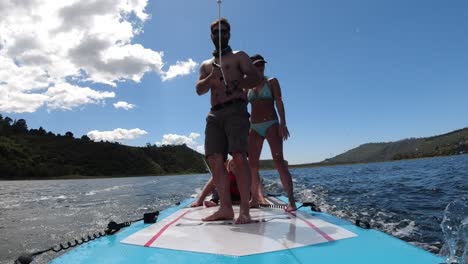 weekend fun for a family being towed by a ski boat on their stand up paddle board