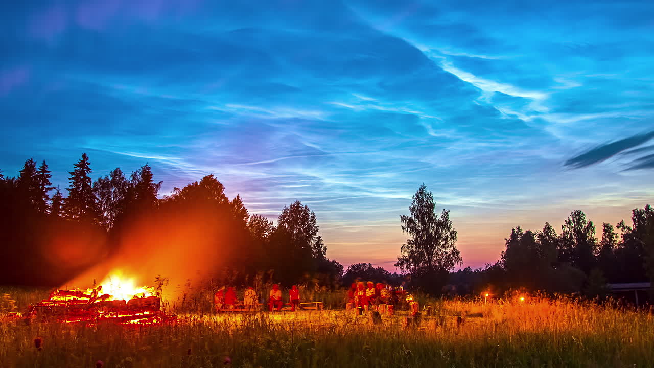 lapso de tiempo de hermosas nubes en el cielo, debajo hay una hoguera y algunas personas disfrutan de su tiempo y los árboles están en su fondo