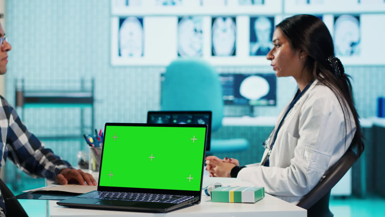 Doctor consulting with patient with a green screen laptop in a clinic