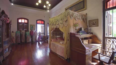 ancient bed decorations and mannequins dressed in vintage clothing displayed inside the pinang peranakan mansion in penang malaysia - panoramic shot