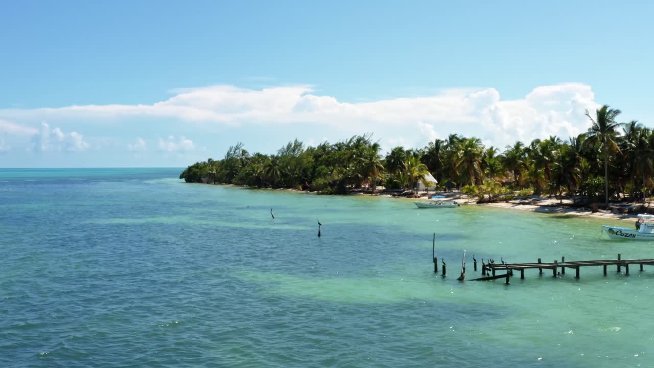 toma aérea de drones de la costa de un pequeño pueblo pesquero en la reserva natural de sian ka'an cerca de tulum, méxico con pequeños botes de pesca, muelles, pelícanos, palmeras y arena blanca en un día de verano