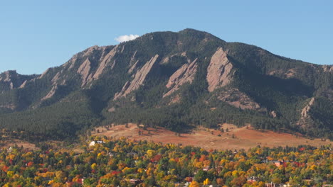 vista aérea de perto das montanhas flatiron em boulder, colorado, cercadas por árvores verdes, vermelhas e amarelas.