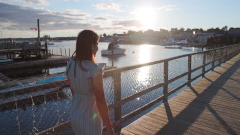 Toma-Panorámica-En-Cámara-Lenta-De-Una-Mujer-Joven-Caminando-En-El-Puente-Peatonal-Del-Puerto-De-Boothbay,-Una-Hermosa-Ciudad-Costera