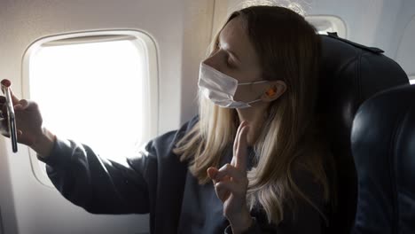 young woman wearing face mask, taking selfie on board