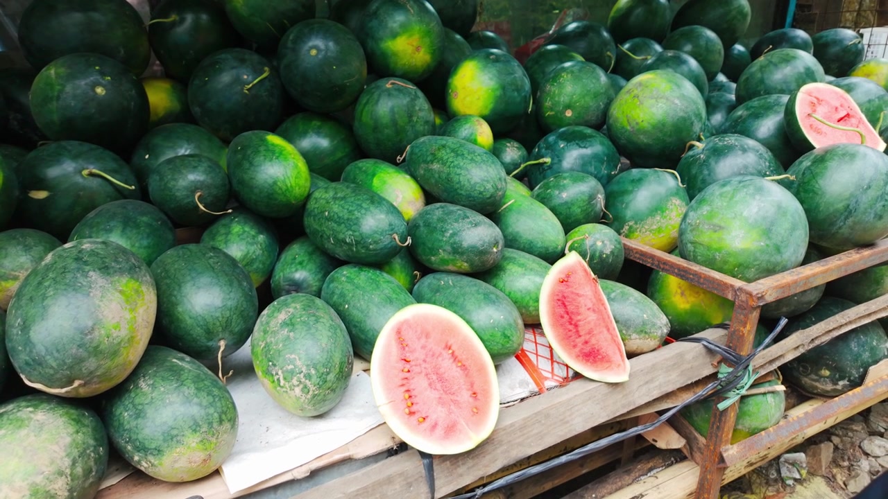 La caméra s'approche d'une grande pile de pastèques fraîches avec des tranches de fruits présentées