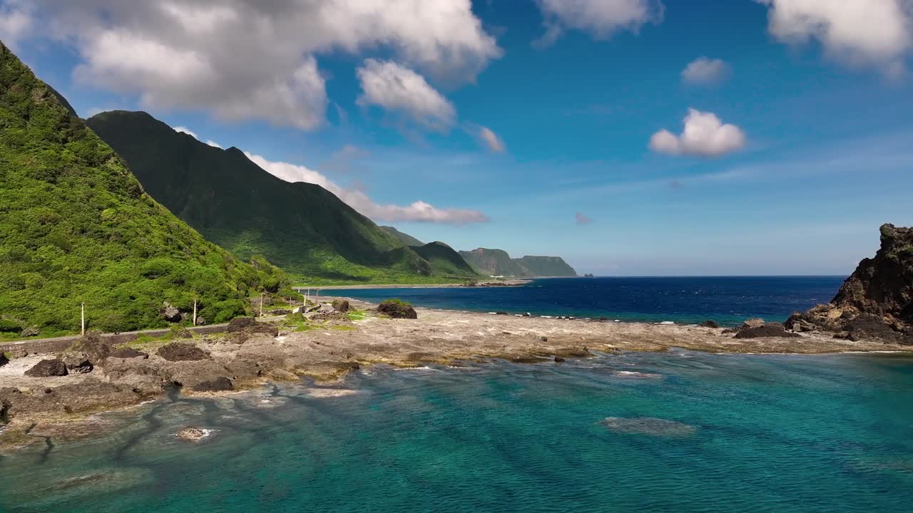 공중 비행 바위 해안선과 투명한 바다 물과 초록색 언덕을 배경으로 - 타이완의 열대 아시아 섬