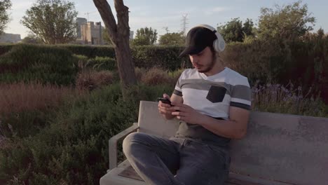 man relaxing in park with headphones and smartphone