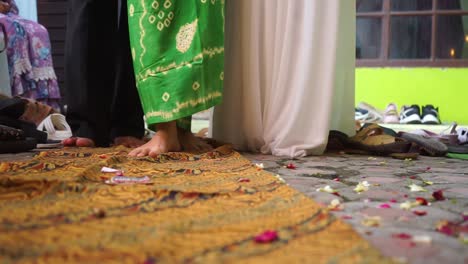 the feet of the bride, father and mother walk on a batik shawl during the "siraman" event which is a traditional javanese or sundanese procession before the wedding