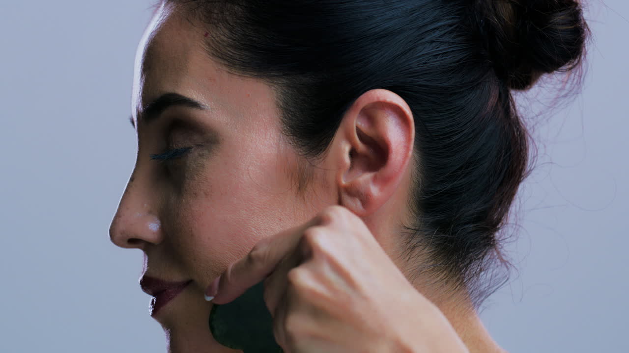 Donna che usa la gua sha per il massaggio facciale