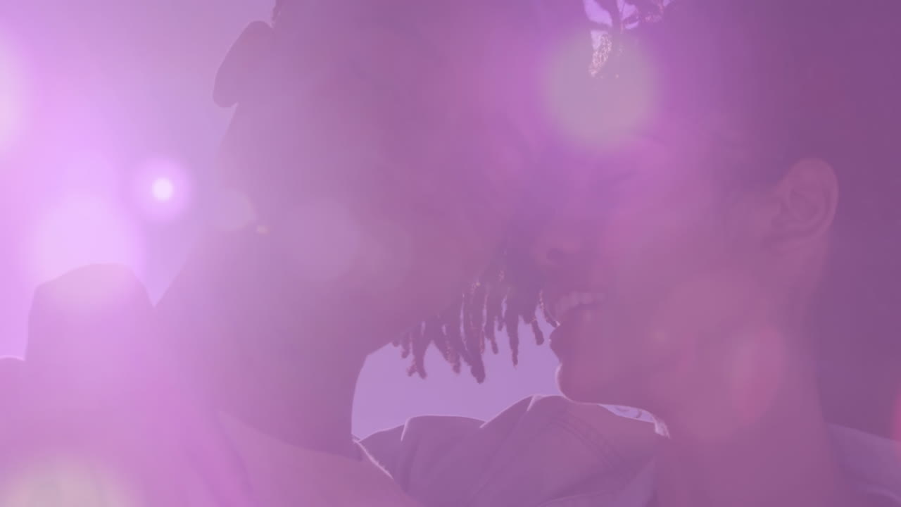 анимация линзовых вспышек над разнообразной парой, обнимающейся и обнимающейся на пляже на фоне неба