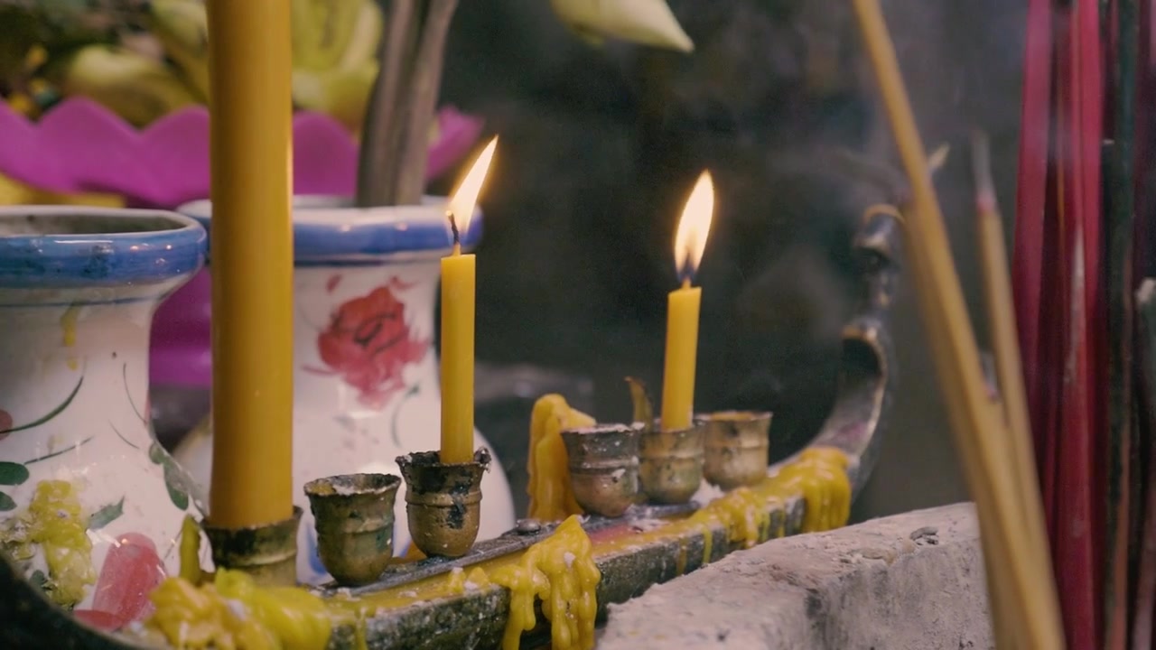 Traditional candles burning with incense sticks inside a temple
