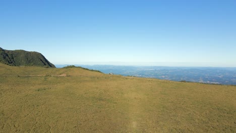 Aerial-flying-over-green-field-landscape-heading-towards-cliff,-Serra-do-Corvo