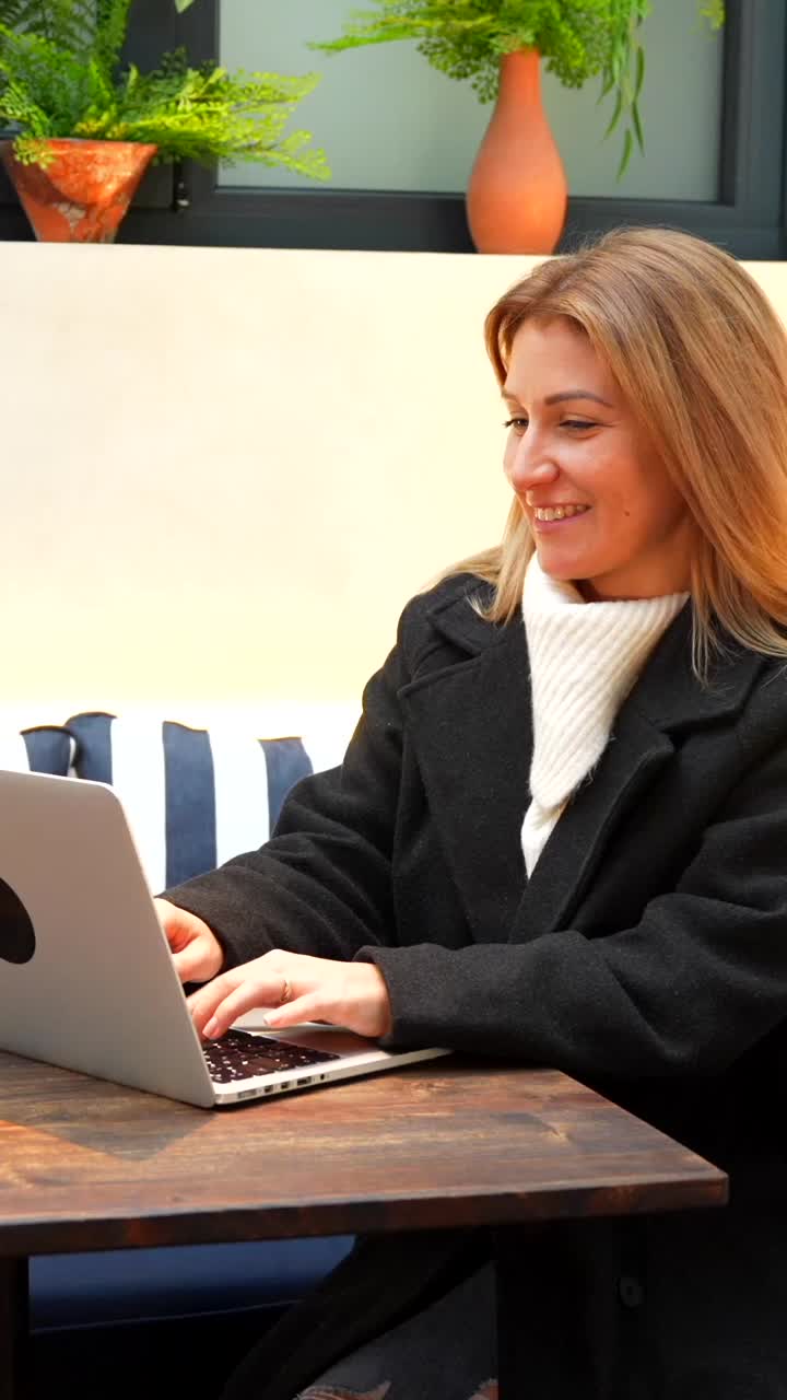 Donna che lavora al computer portatile e parla al telefono