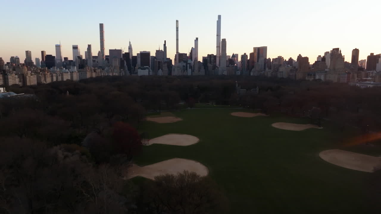 Aerial view over the Great Lawn, approaching the midtown skyline, in Central park, NY, USA