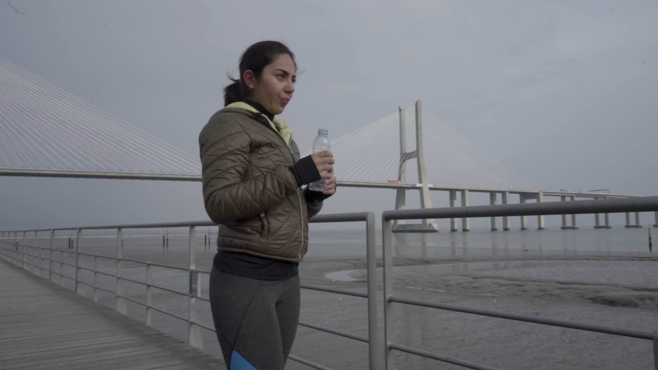 Mujer hermosa cansada bebiendo agua después de entrenar