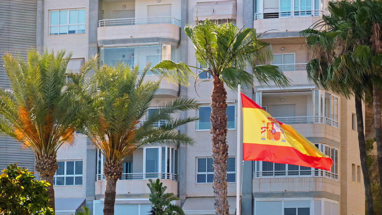 Spansk flag, der vajer langs lejlighederne ved stranden i Benidorm, Alicante