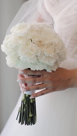 Close-up-of-a-bride-holding-flowers-in-bedroom