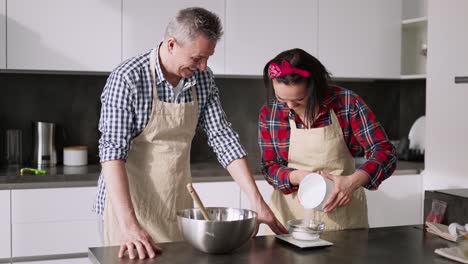 couple cooking together, woman measuring sugar portion