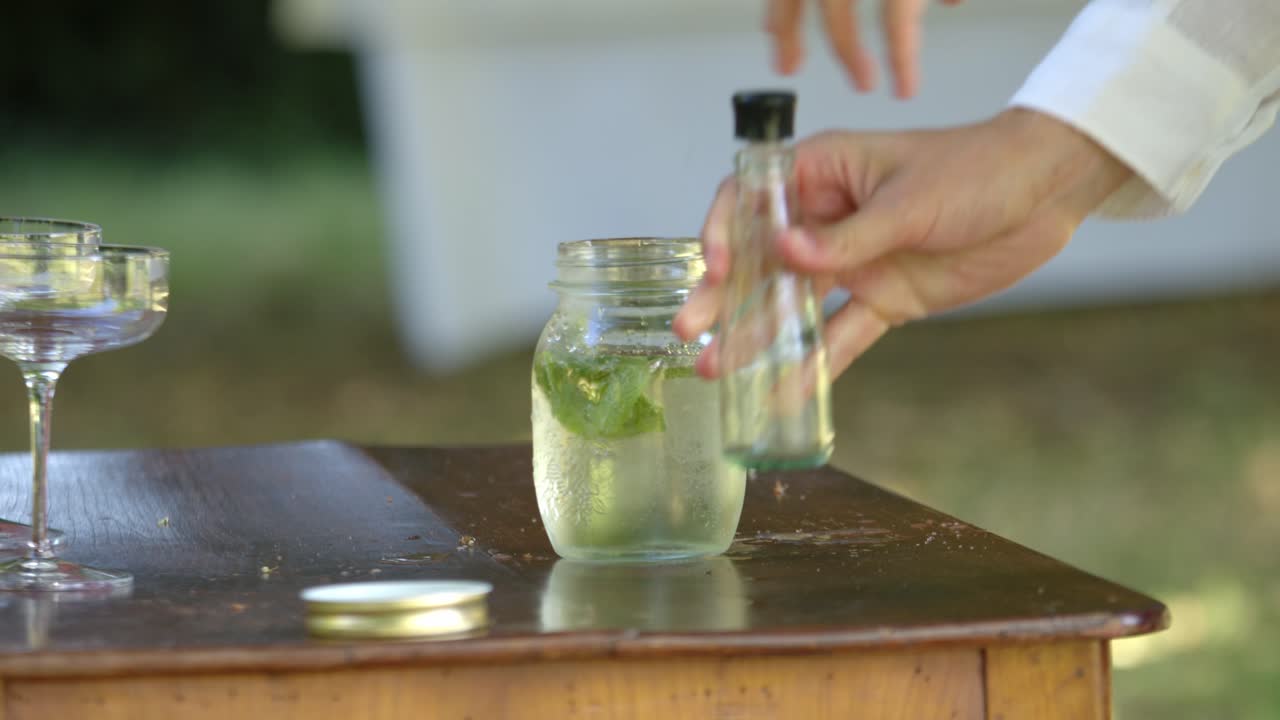 Person Pouring Soda Water In A Mojito Cocktail. Close-up, Slow Motion