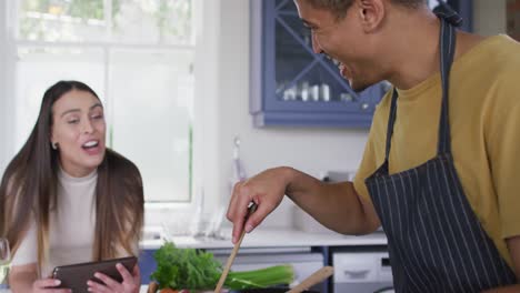 Glückliches-Gemischtrassiges-Paar,-Das-Zusammen-Kocht-Und-In-Der-Küche-Lacht