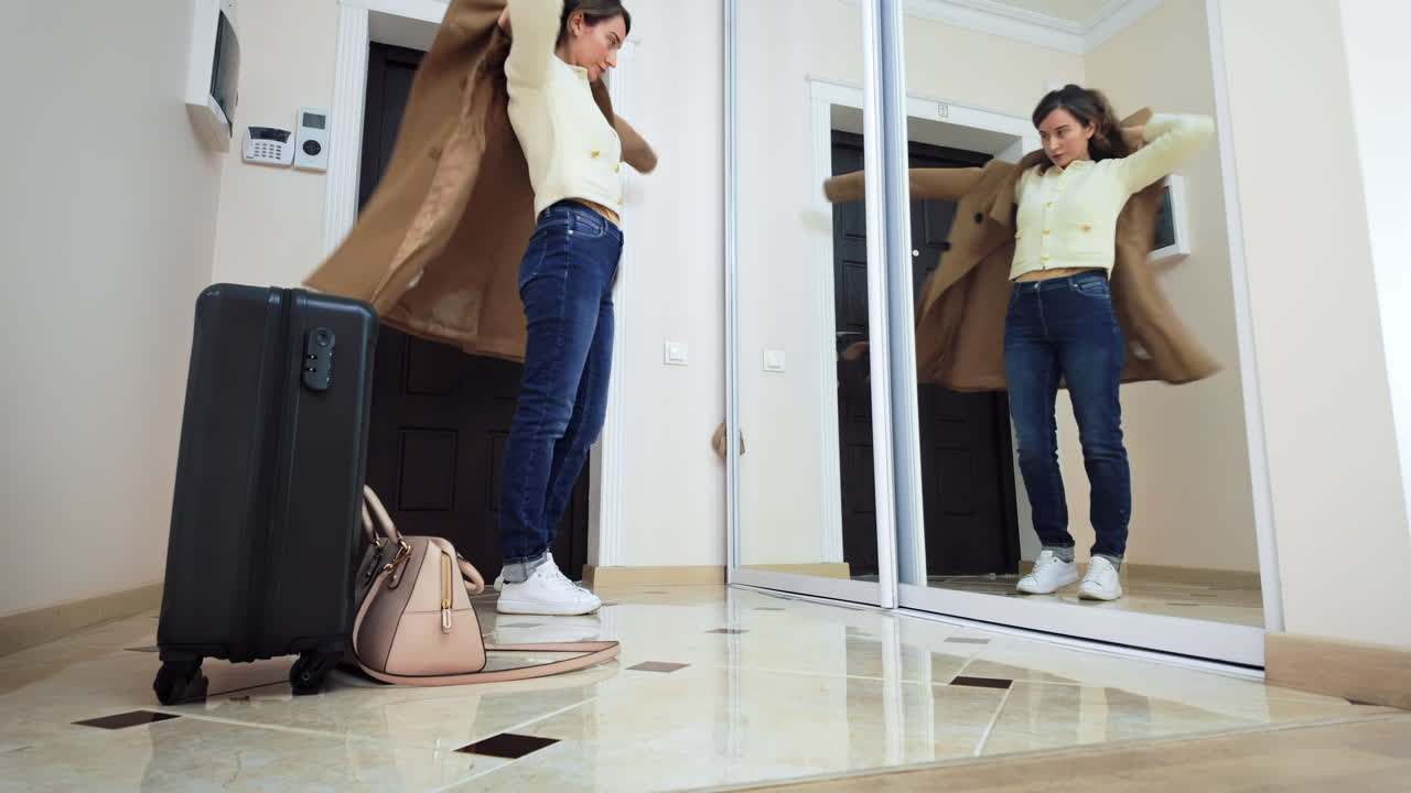 Woman putting on a brown coat, picking up her bags and leaving out the door
