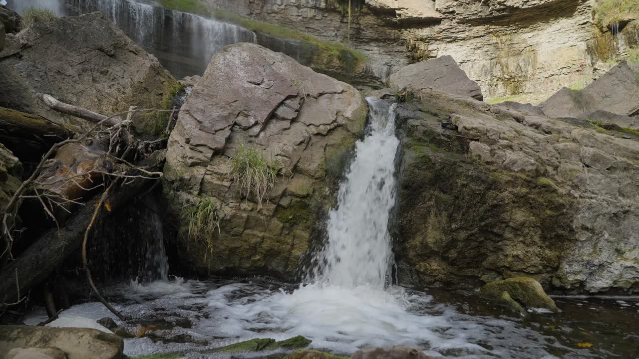 Water flows over rocks in a serene natural setting with mossy details and calming ambiance