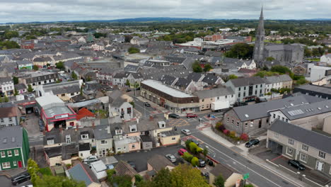Aerial-panoramic-footage-of-buildings-in-town-centre.-Tilt-down-focusing-on-cars-passing-through-street-intersection.-Ennis,-Ireland