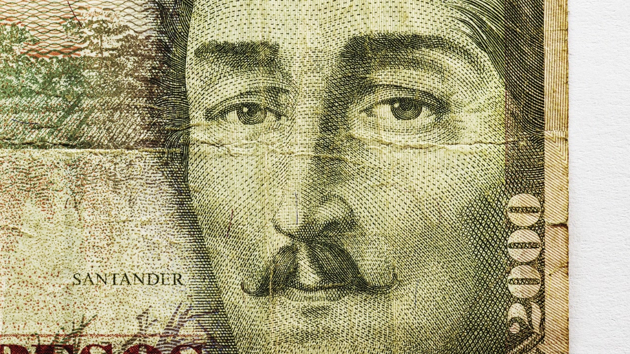 Close pan of a worn 2000 pesos Colombian note with portrait and fold lines