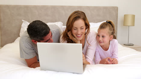 family using laptop together on bed