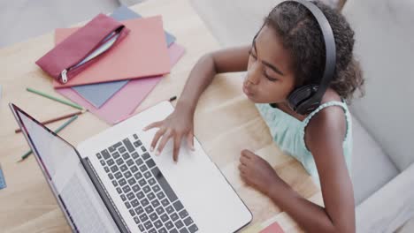 chica afroamericana sentada en una mesa, usando una computadora portátil para una lección en línea, cámara lenta