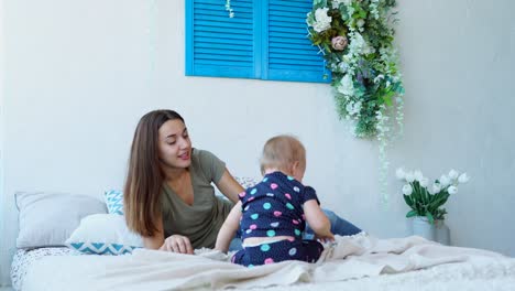 mother and baby playing on bed
