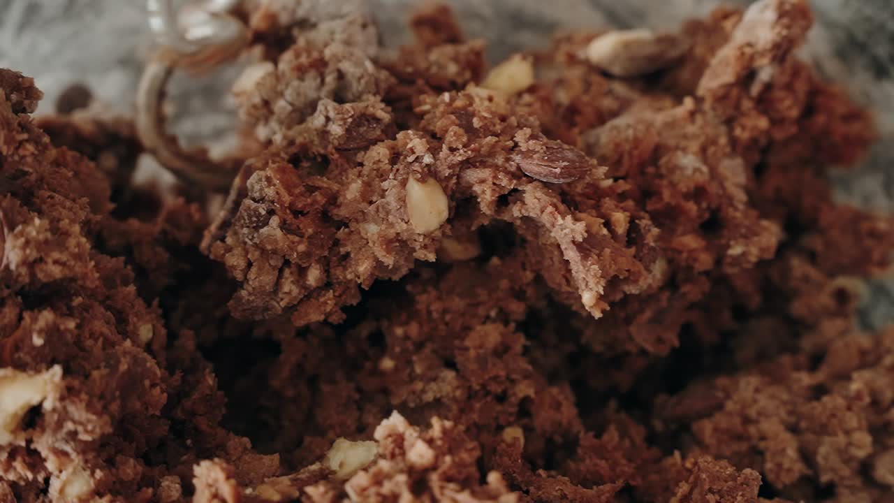 Macro primo piano di un ricco impasto per biscotti al cioccolato con noci mescolato da un mixer elettrico