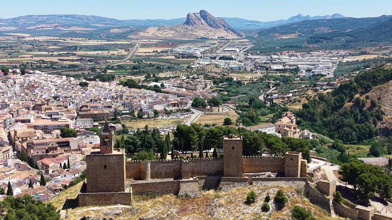 Vista aérea con dron de la fortaleza de la Alcazaba con vistas a Antequera, España, con la icónica montaña Peña de los Enamorados y el campo circundante.