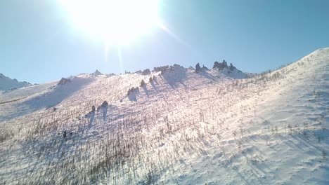 Escalar-Una-Montaña-Nevada-Y-Soleada-En-Un-Dron