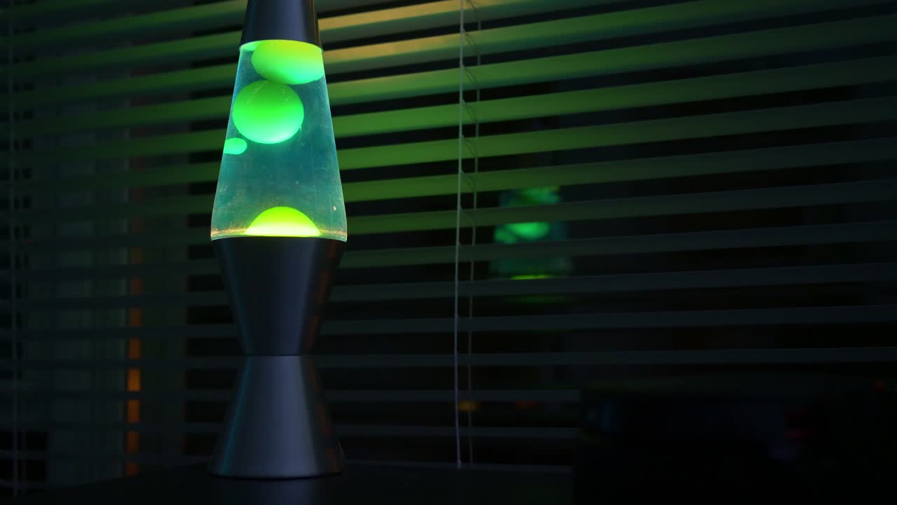 Green lava lamp time lapse in a dark room-office near a window