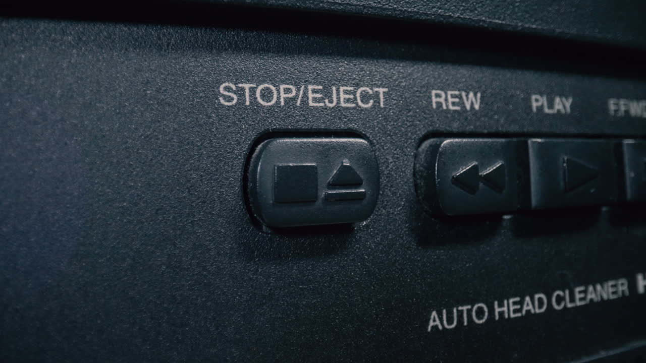 primer plano, toma macro de un dedo presionando el botón "stop" en el panel de control de un reproductor de vcr antiguo