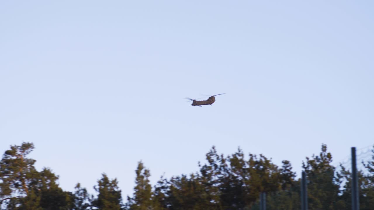 Army Boeing Chinooks flying over village, trees and forests