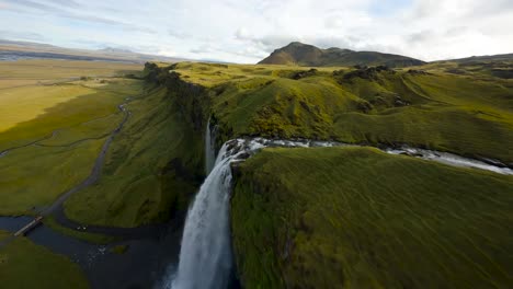 fpv aéreo filmado a lo largo de la cresta de la cascada de seljalandsfoss bajo luz dorada