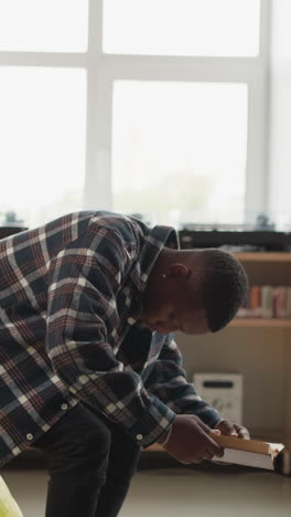 un hombre se sienta en una bolsa de frijoles en la biblioteca de la universidad. un estudiante afroamericano disfruta leyendo con comodidad en una moderna librería. educación y pasatiempo