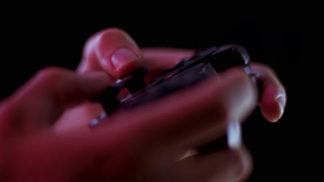 playing video games in a darkened room with a black background close up on a small controller joystick playing quickly soft focus