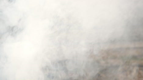 bramando humo espeso que se eleva al aire libre con una cerca programada detrás