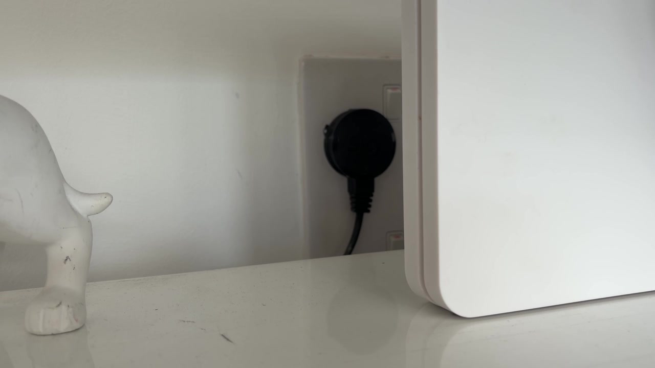 White WiFi Router Connected to Power on a Home Desk