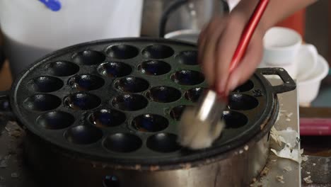 oiling up and pereparing a krok griddle pan for making famous thai coconut milk rice flour desert kanom krok