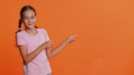 child girl kid showing thumbs up and pointing on blank space place for advertisement promotion logo