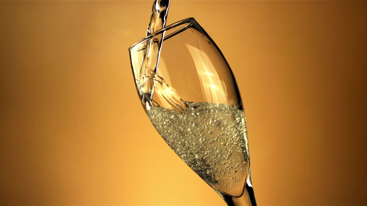 Versamento al rallentatore di champagne dorato e frizzante in un bicchiere a flûte
