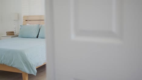 Bedroom-with-bed-and-night-table-seen-from-behind-door