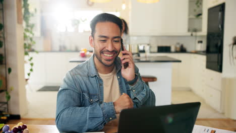 hombre trabajando desde casa en una computadora portátil y hablando por teléfono en la cocina