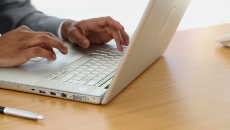 un hombre de negocios escribiendo en una computadora portátil.
