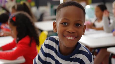 Front-view-of-African-american-schoolboy-looking-at-camera-in-the-classroom-4k