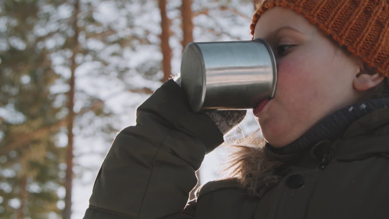 Bambina che beve tè caldo durante un'escursione invernale
